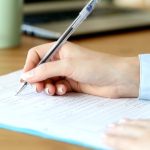 Close up of a woman hand filling form on a table at home or office